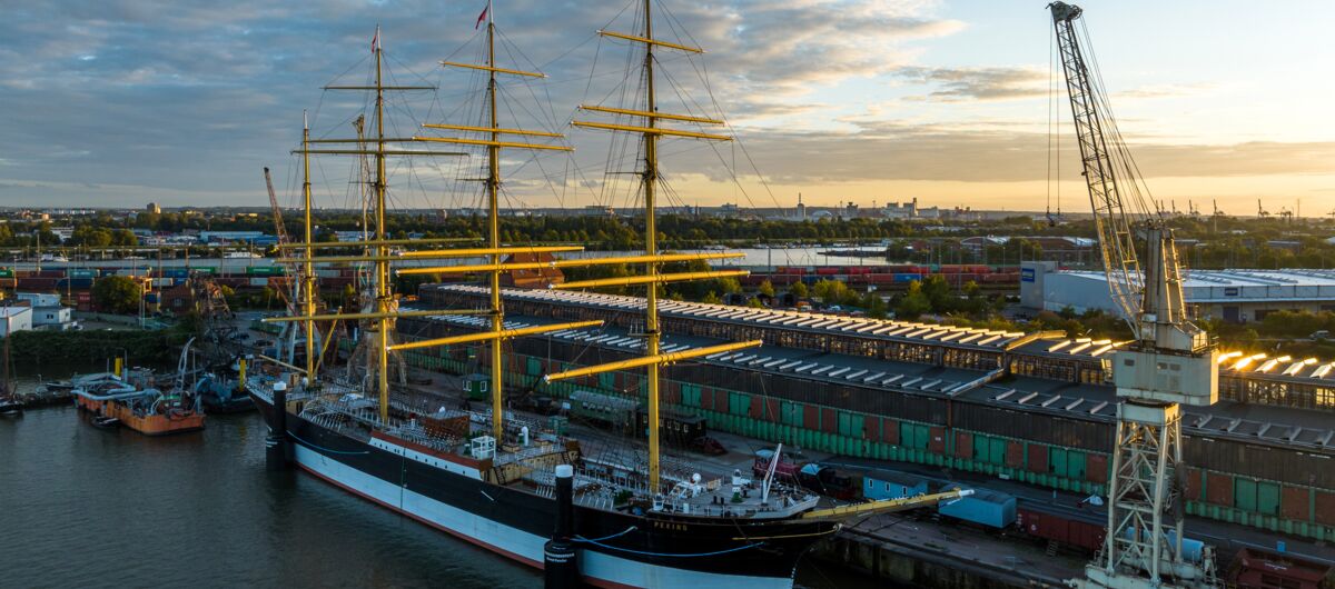 Sonnenaufgang im Hafen, in dem der Frachtsegler Peking vor Anker liegt. Es ist ein vier Masten tragendes Schiff mit insgesamt 32 Segeln, die eingeholt sind.