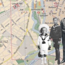 Vier männliche Personen in verschiedenen Altersstadien (von Klein-, über Schulkind zum Teenager und jungen Mann) stehen vor einer Landkarte, die das Stadtzentrum von Lübeck zeigt. Die Karte ist farbig, die Personen in schwarz-weiß abgebildet.