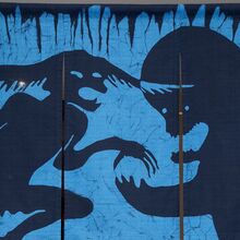 Drei an einer Stange hängende Stoffbahnen bilden zusammen ein Bild. Auf einem blauen Hintergrund sind in dunkelblau zwei Phantasiegestalten abgebildet, die sich gegenüber stehen und miteinander zu kämpfen scheinen.