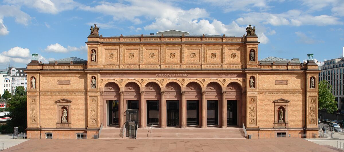 Foto des Eingangsportals der Hamburger Kunsthalle. Sechs Säulen dominieren die historische Steinfassade. Treppenstufen führen zu den Säulen. Zwischen der ersten und zweiten Säule von links sind die Treppen durch einen Fahrstuhl unterbrochen.