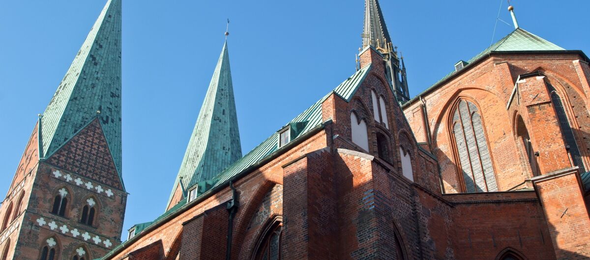 Roter BAckstein bildet das Kirchenschiff, welches mit vielen Ecken und Wickeln und seinen zwei großen und einem kleinen Turm in den blauen Himmel aufragen. Die gotischen Elemente spiegeln sich an Fenstersimsen, Toren, Bögen und dem Turm wider.