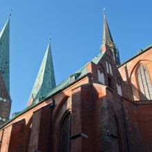 Roter BAckstein bildet das Kirchenschiff, welches mit vielen Ecken und Wickeln und seinen zwei großen und einem kleinen Turm in den blauen Himmel aufragen. Die gotischen Elemente spiegeln sich an Fenstersimsen, Toren, Bögen und dem Turm wider.