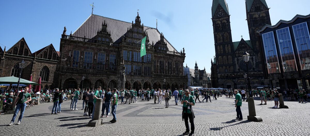 Foto des Bremer Rathaus bei Sonnenschein. Auf dem Platz davor ist reges Treiben. Viele Menschen sind zu sehen, Restaurants haben ihre Außengastonomie geöffnet.
