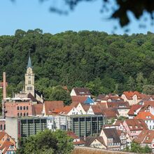 Foto von der Stadt Schwäbisch Hall. Im Hintergrund steht ein Wald. Die Kunsthalle Würth steht im Zentrum des Fotos. Sie besticht durch eine Gläserne Front. Drumherum stehen Fachwerkhäuser, dahinter eine Kirche mit Turm.