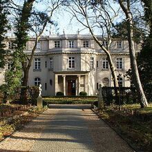 Foto der Villa Marlier, ein prunkvolles Gebäude in einem Park. Der Eingangsbereich ist ein runder Vorbau mit Säulen und einem Balkon.