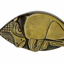 Foto einer Tierplastik. Zu sehen ist ein liegendes Kälbchen. Die metallische platte Plastik ist auf den erhobenen Flächen golden, die tieferliegenden Flächen sind schwarz.