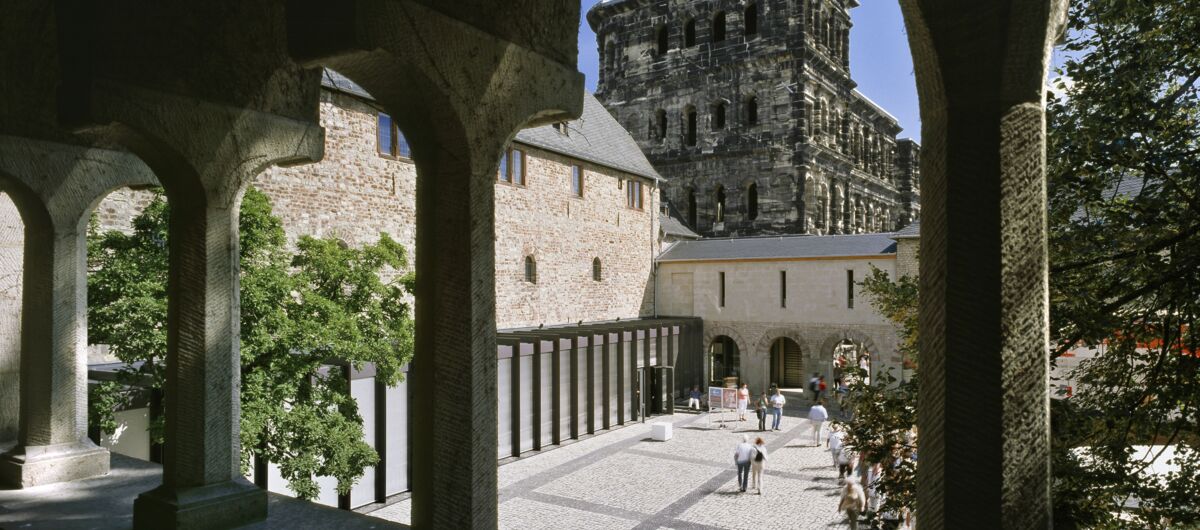 Ausblick durch Rundbögen des Stadtmuseum Simeonstift in den Innenhof. Im Hintergrund ist die Porta Nigra zu sehen.