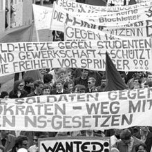 Schwarz-weiß Foto eines Demonstrationszugs am 11.05.1968 gegen die Notstandsgesetze. Größtenteils jüngere Menschen sind zu sehen. Sie halten weiße Transparente - beschrieben mit ihren Forderungen - hoch.