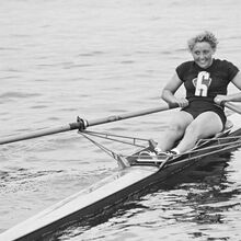 Schwarz-weiß Foto von der Ruderin Lieselotte Proll bei der Frühjahrsregatta in Grünau am 22.5.1954. Sie ist lachend auf dem Wasser am Rudern.